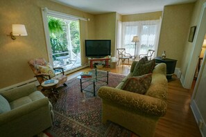 Relax in this inviting living room with a large flat-screen TV, comfortable seating area, and large windows.