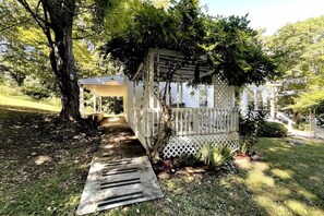 Enjoy a peaceful retreat on the covered porch, surrounded by lush gardens and a serene natural setting.