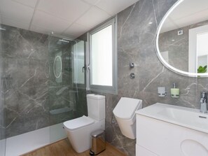 Een moderne badkamer met een douchecabine, toilet, wastafel en een wastafelmeubel.