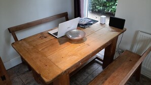 Une table en bois avec un ordinateur portable, un saladier en verre et un haut-parleur.