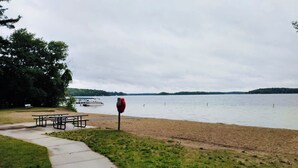 Een park aan het meer met picknicktafels en een rood bord.