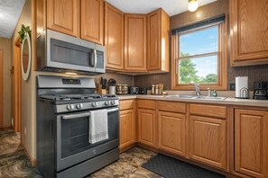 Una cocina moderna con armarios de madera, estufa de acero inoxidable y microondas.