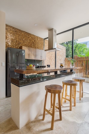 A modern kitchen with a stone wall, wooden bar stools, and a built-in island.