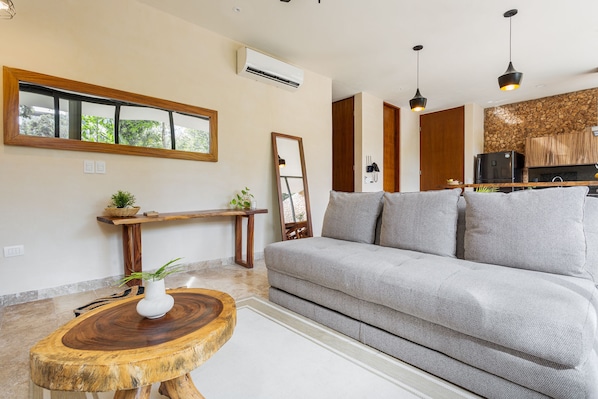 A modern living room with a grey sofa, wooden side tables, and a large mirror.