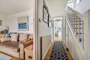 A hallway with a brown leather sofa, a radiator, and a patterned rug.