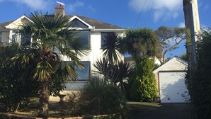 A two-story house with a garage, surrounded by palm trees and a garden. - 5 Bed House - Sleeps 15 - Pets - Garden - Parking (Kingsbridge)