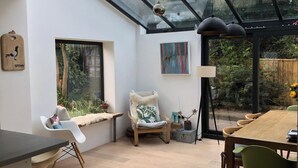 A modern interior with a glass ceiling, a dining area, and a cozy seating space with a chair and a bench. - 5 Bed House - Sleeps 15 - Pets - Garden - Parking (Kingsbridge)