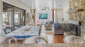 A spacious living area with a dining table, sofas, and a stone fireplace. - Bayfront to Beach Beauty Access to bay (Dewey Beach)