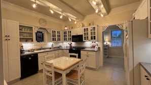 A spacious kitchen with white cabinetry, a central island, and a dining area. - Charming Victorian, Private Hot Tub (New Buffalo)