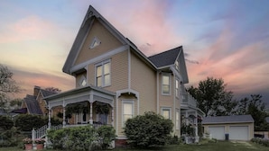 A two-story house with a wrap-around porch, a garage, and a well-maintained lawn. - Charming Victorian, Private Hot Tub (New Buffalo)