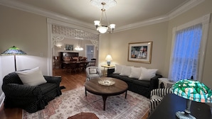 A living room with a dining area, featuring a chandelier, patterned rug, and a framed picture on the wall. - Charming Victorian, Private Hot Tub (New Buffalo)