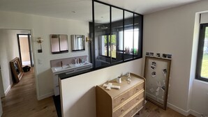 Ein modernes Badezimmer mit einem großen Spiegel, einem Waschbecken und einem Waschtisch. Außerdem steht dort ein Holzschrank und ein gerahmtes Bild hängt an der Wand.