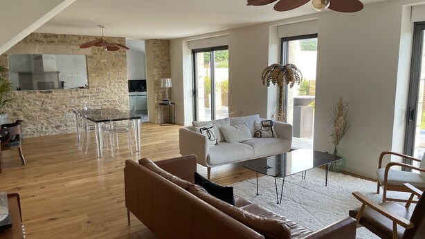 Ein großzügiger Wohnbereich mit einem modernen Sofa, einem Esstisch mit Stühlen und einer Küche im Hintergrund.