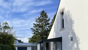 Ein modernes Haus mit weißer Fassade, einem steinernen Fundament und einem gepflegten Rasen.