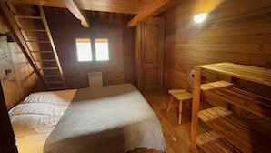 A cozy wooden cabin room with a bed, a ladder, a small table, and a window. - Chalet, Ground floor, parking, tv, ski locker, 44m², Le Grand Bornand (Le Grand-Bornand)