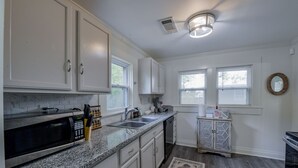 A kitchen with white cabinets, a microwave, a sink, and a dishwasher.