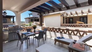 Un patio al aire libre con una parrilla, comedor y zona de estar.