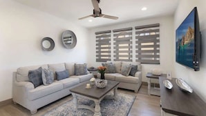 Una sala de estar moderna con un sofá gris, una mesa de centro y un televisor.
