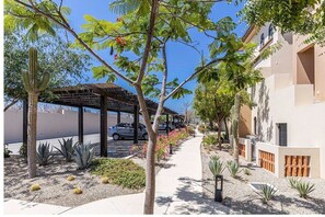 Stroll along the paved walkway, lined with lush plants, to a serene outdoor seating area.