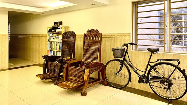 Una habitación con un banco de madera, una estantería y una bicicleta apoyada contra la pared.