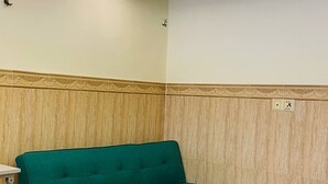 Un sofá color turquesa en una habitación con suelo de baldosas y pared de paneles de madera.