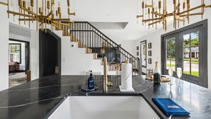 A modern kitchen with a black marble countertop, a stainless steel sink, and a built-in wine cooler. - Unwind in Style | The Longboard (Mount Pleasant)