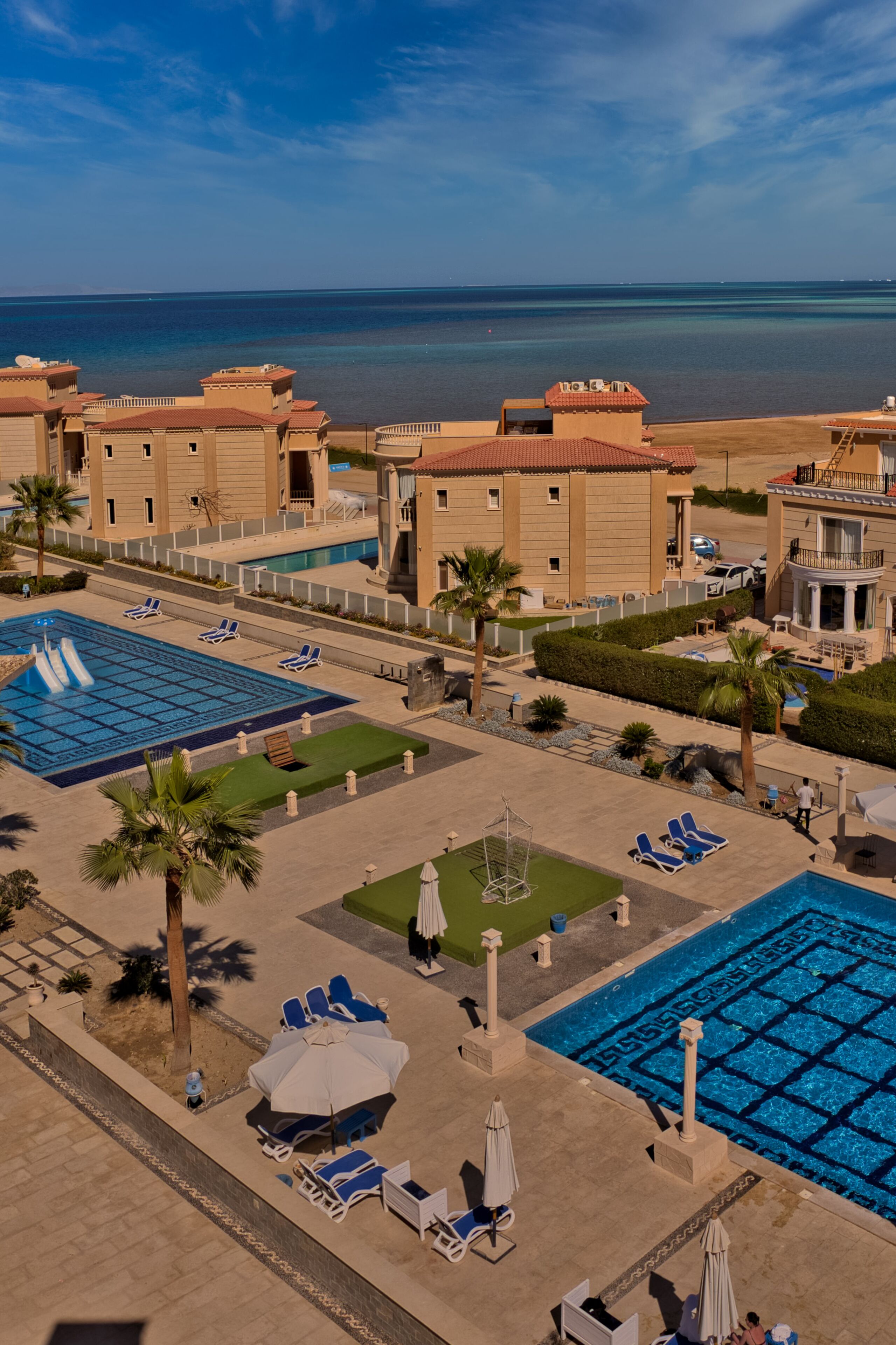 Un resort con varias piscinas, tumbonas y palmeras.