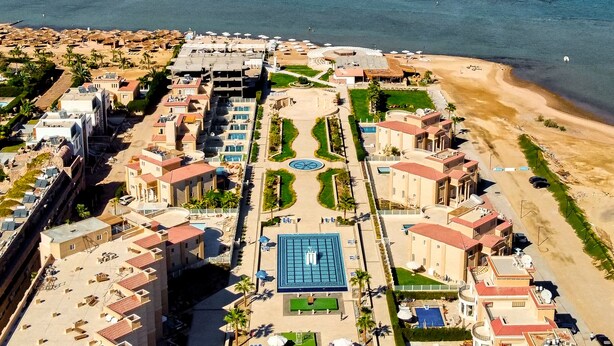 An aerial view of a coastal resort with multiple buildings, a central swimming pool, and a beach area. - Selena Bay Resort (Hurghada)