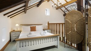 A bedroom with a wooden bed, white bedding, a nightstand with a lamp, and a large woven basket. - Keiras Cottage - Three Bedroom House, Sleeps 6 (Ambleside)