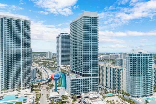 A high-rise hotel with multiple floors, a swimming pool, and a prominent curved building in the center.