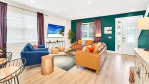 Una sala de estar moderna con un sofá azul, un sofá naranja y un comedor con mesa y sillas.