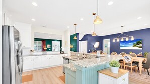Una cocina moderna con armarios blancos, encimera de granito y pared de acento azul.