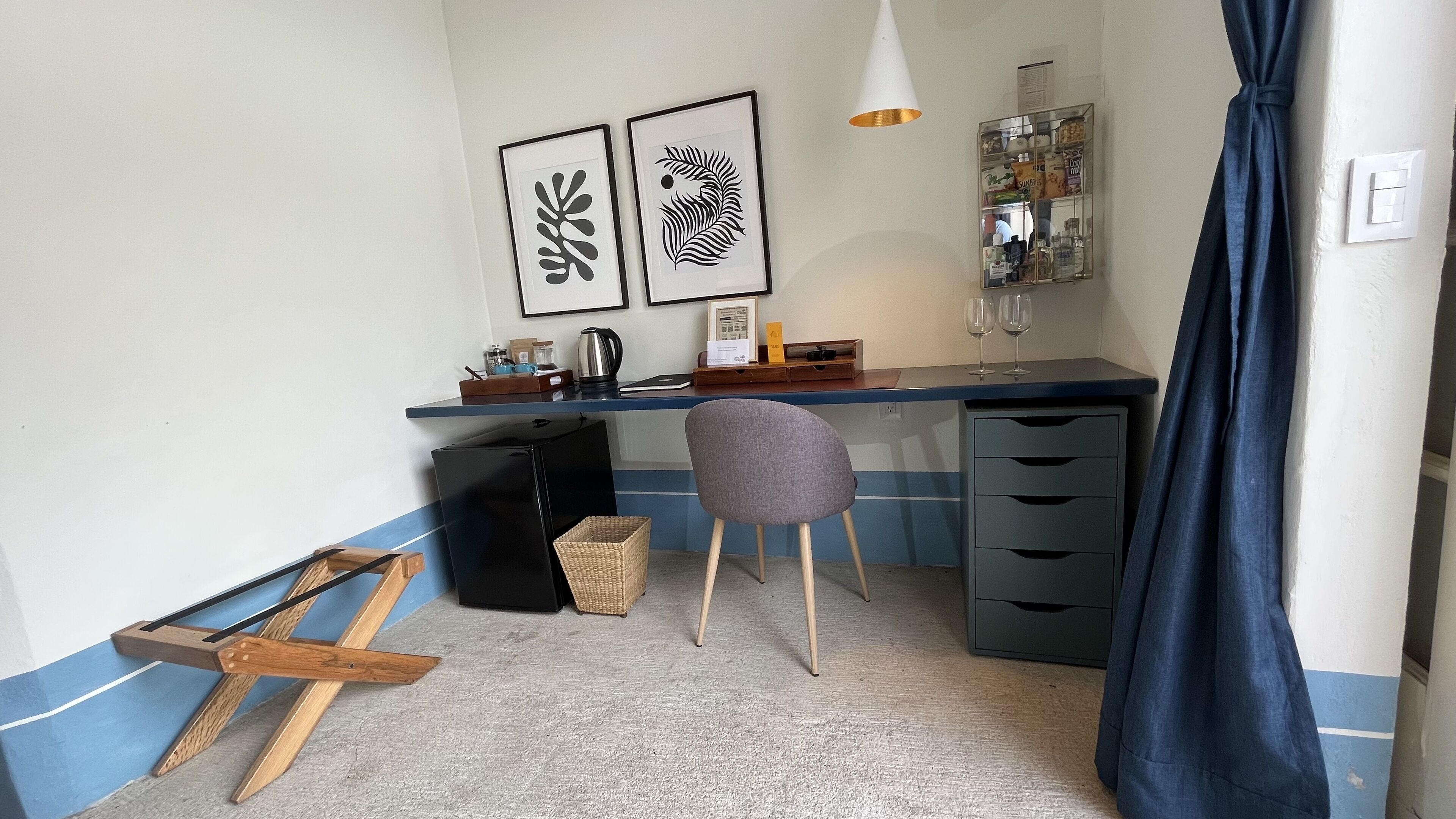 Una habitación pequeña con escritorio, silla y una kitchenette.
