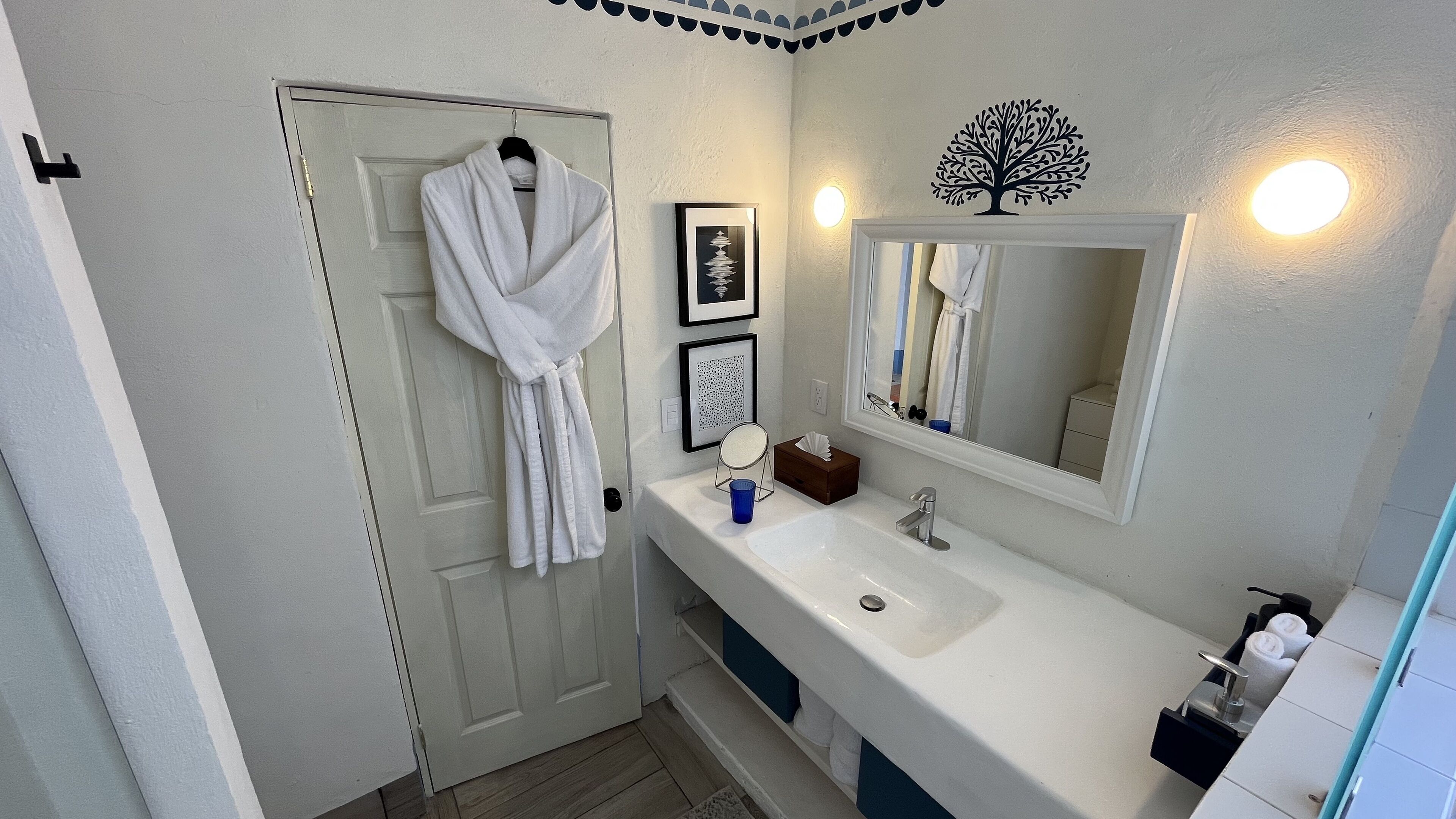 A bathroom with a white sink, a mirror, a towel rack, and a framed picture on the wall.