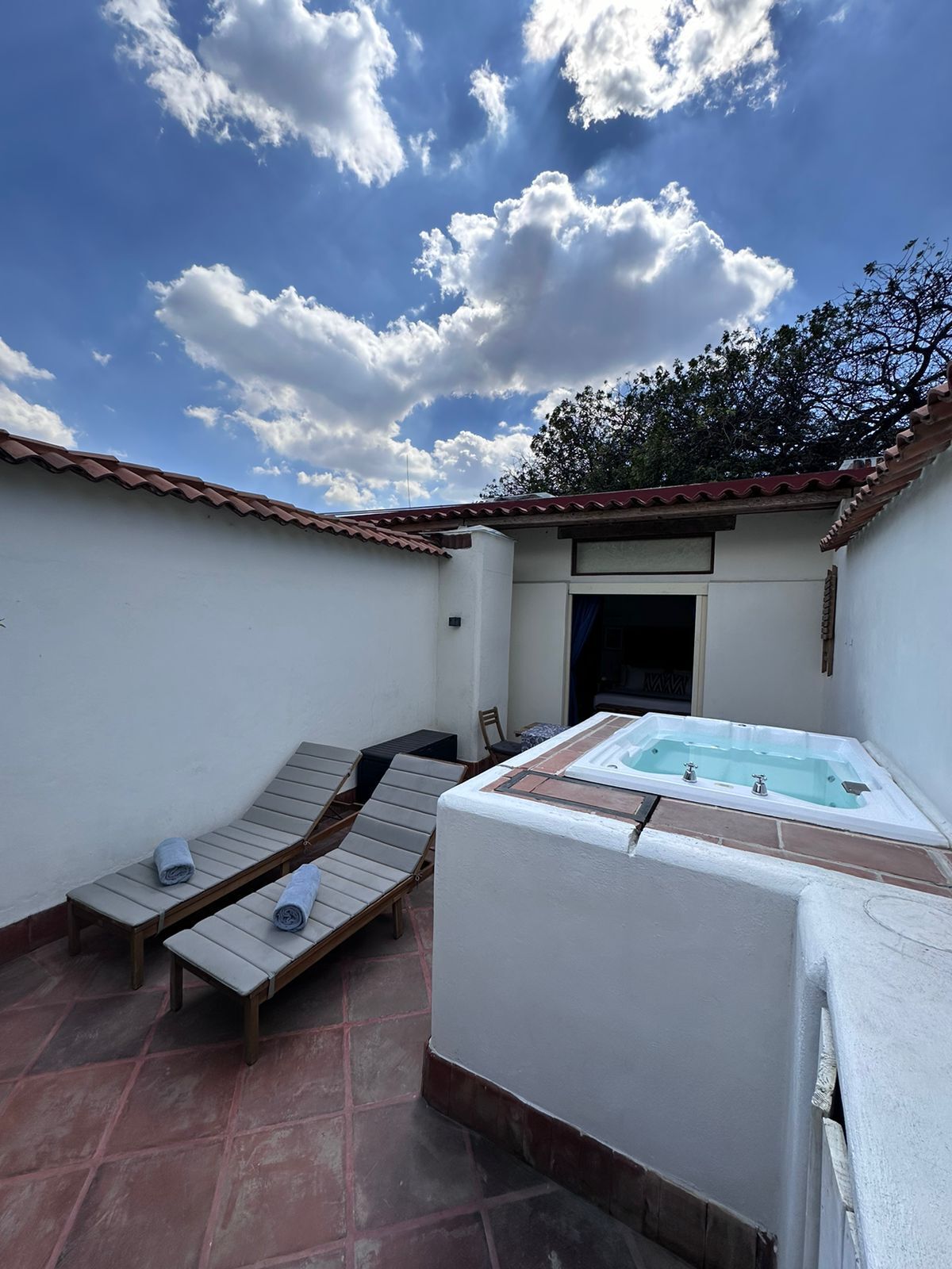 A spa area with a hot tub, two lounge chairs, and a tiled floor.