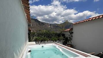 A hot tub in a courtyard with a mountain backdrop.