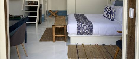 Une chambre à coucher comprenant un lit, un bureau, une chaise, un banc, un escalier et une petite table.