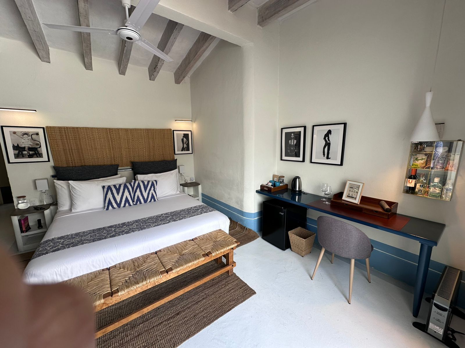 A hotel room with a bed, desk, chair, and ceiling fan.