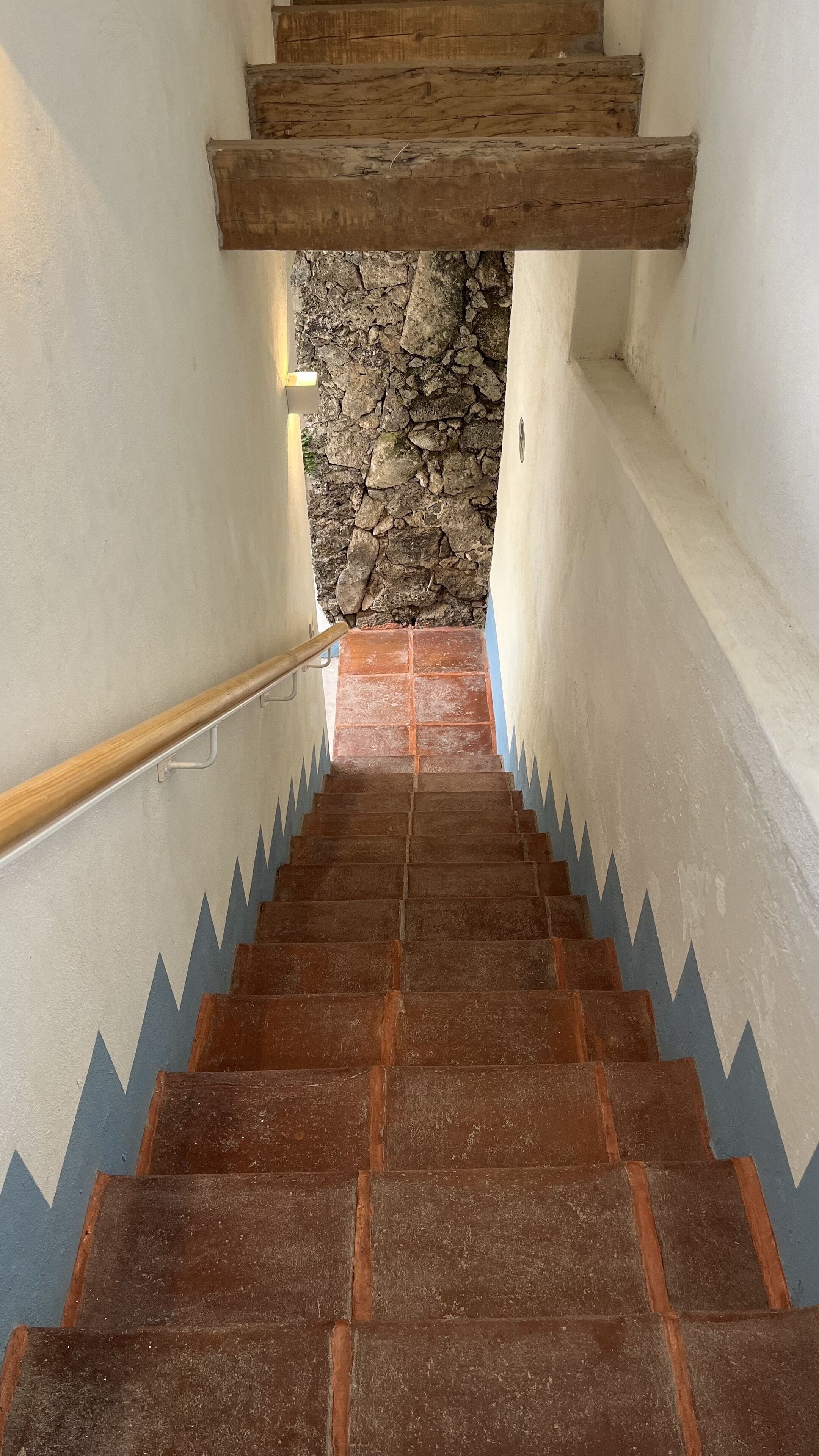 Una escalera con paredes de piedra y barandillas de madera.