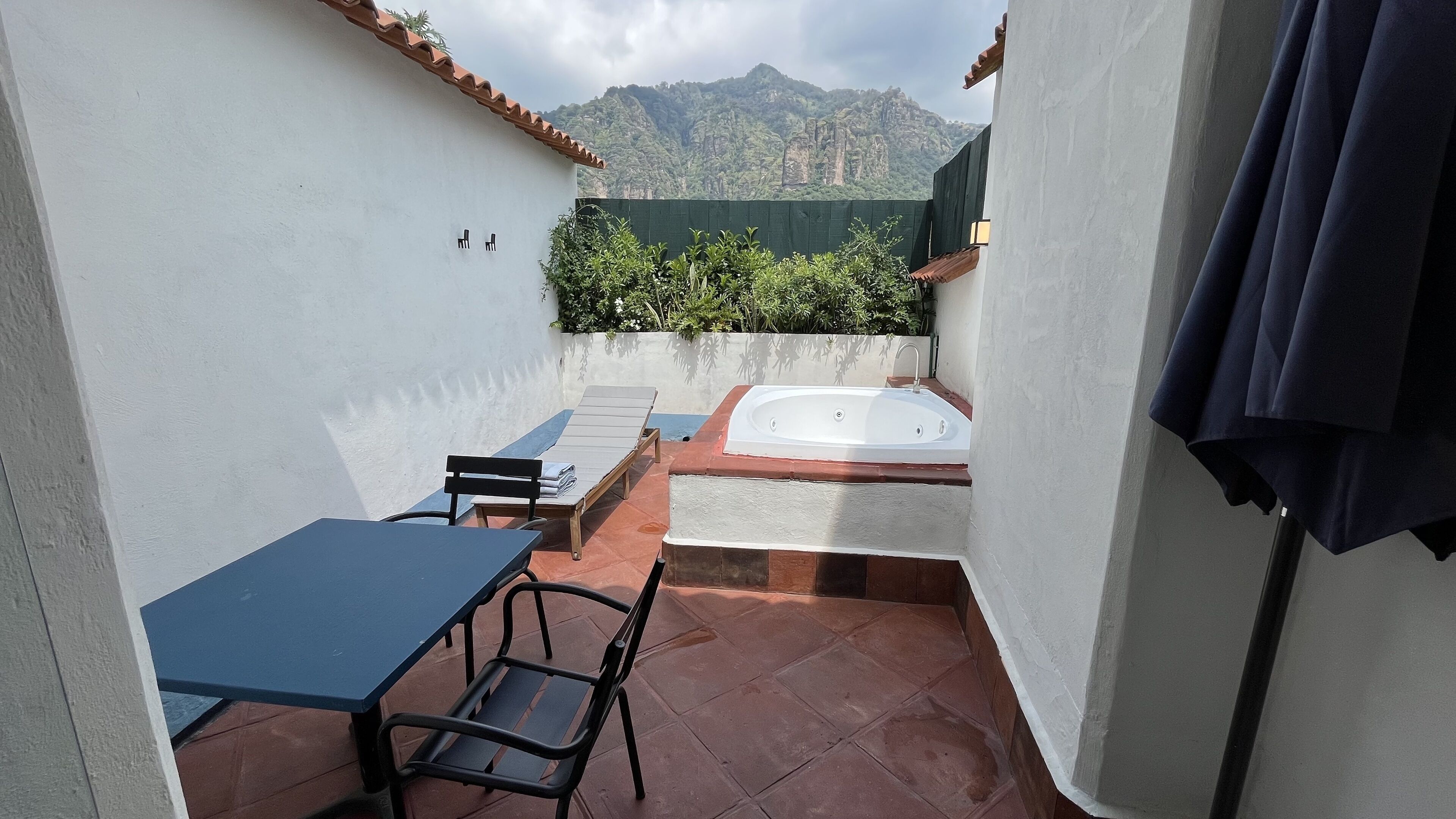 Une petite terrasse extérieure avec une table et des chaises, un jacuzzi et une vue sur les montagnes.
