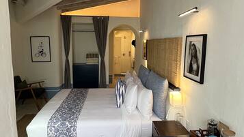 A hotel room with a bed, a desk, and a shower area.