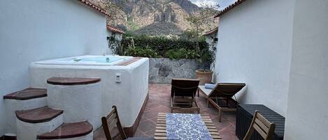 Une terrasse sur le toit avec un jacuzzi, des sièges d’extérieur et une vue sur les montagnes.