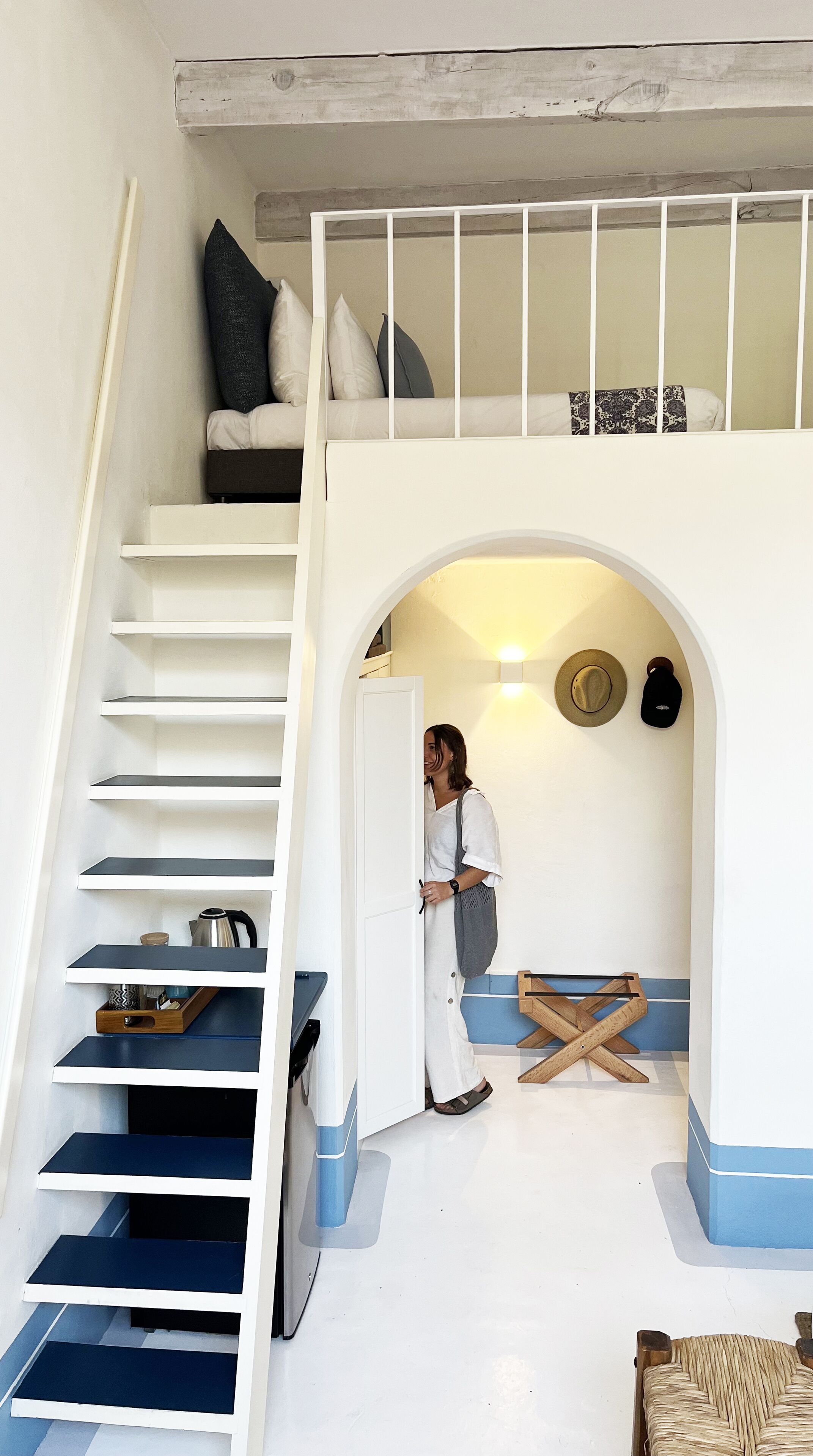Eine Treppe führt zu einem Schlafbereich mit Hochbett, eine Person steht am Fuß der Treppe.