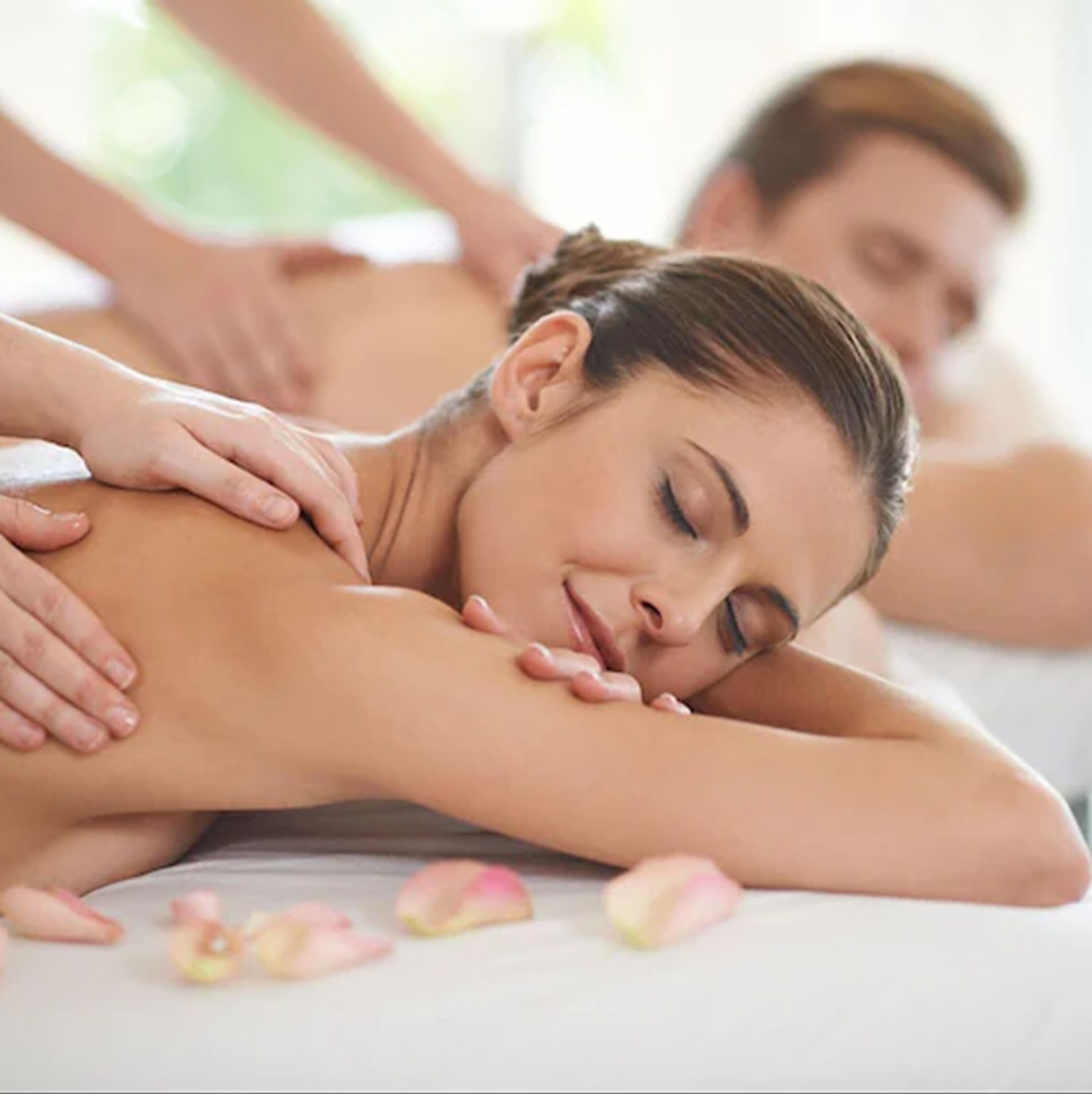 Un ambiente de spa con una camilla de masaje y una persona recibiendo un masaje en la espalda.