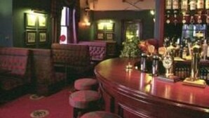 A bar area with a counter, stools, and a variety of bottles. - Lovat Arms Hotel (Beauly)