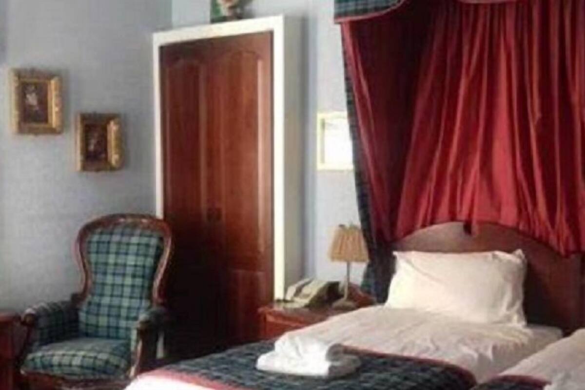 A hotel room with a bed, a chair, and a door.