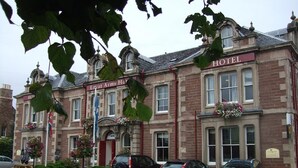 A historic building with a 'HOTEL' sign, multiple windows, and parked cars. - Lovat Arms Hotel (Beauly)