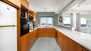 Een moderne keuken met houten kastjes, een inbouwoven en een groot raam met uitzicht over de stad.
