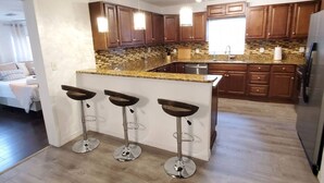 Una cocina moderna con armarios de madera, encimera de granito y una isla integrada con taburetes de bar.