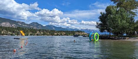 A lake with mountains in the background, a yellow floating platform, and colorful rings in the water.